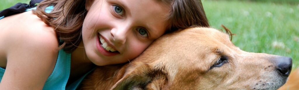 A young girl hugging her dog and posing for a picture.
