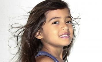 a young girl posing for the camera and smiling.