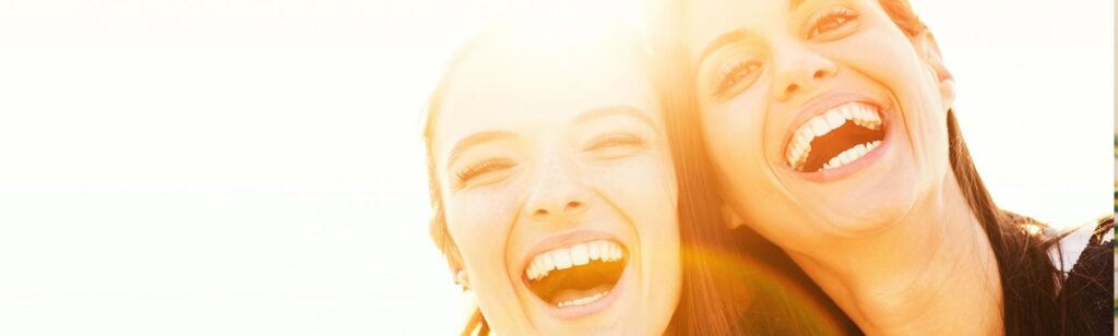 two female adults smiling and enjoying the sunlight.