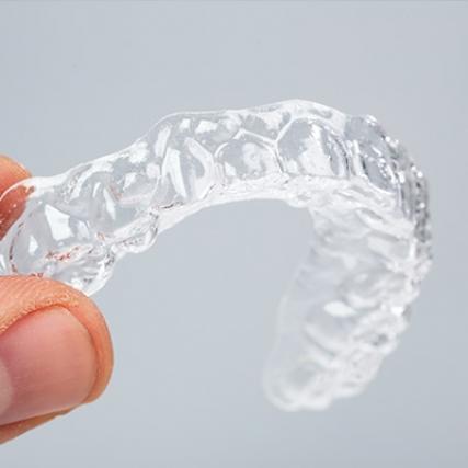 A hand holding a set of Invisalign clear aligners