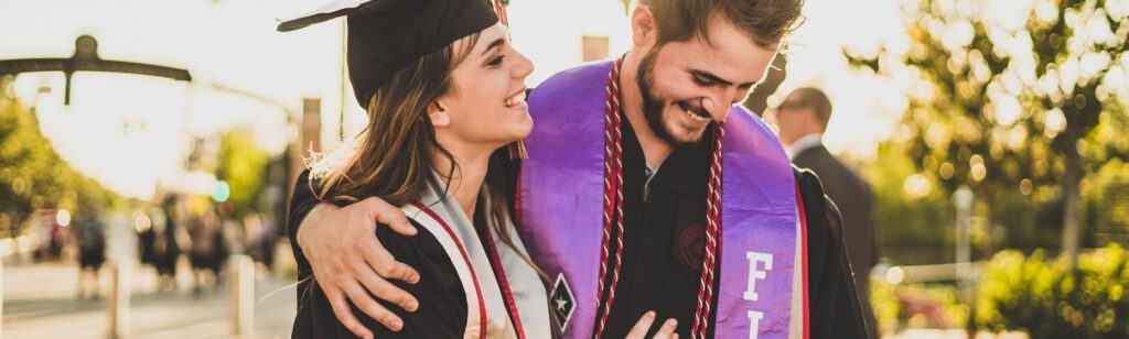 A couple celebrating their graduation, while hugging each other.