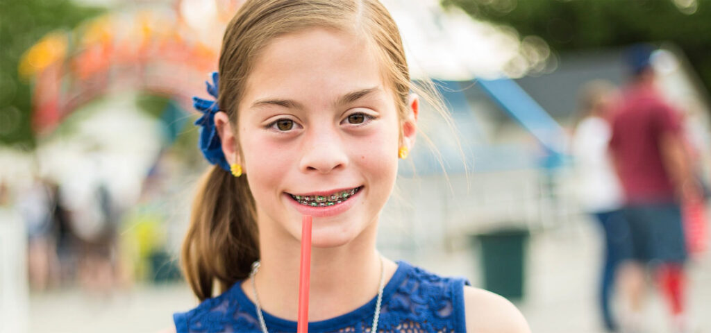 Smiling girl with braces learning about what drinks are bad for teeth
