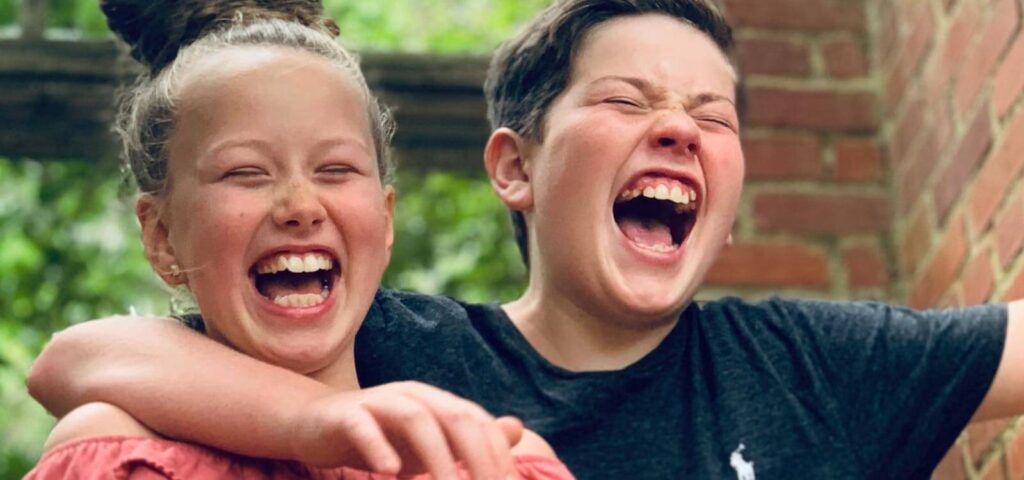brother and sister laugh and hug after learning what causes crowded teeth