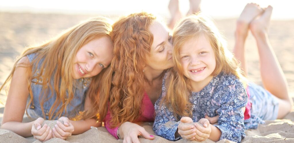 mom whispers into daughter's ear the difference between Invisalign buttons vs attachments